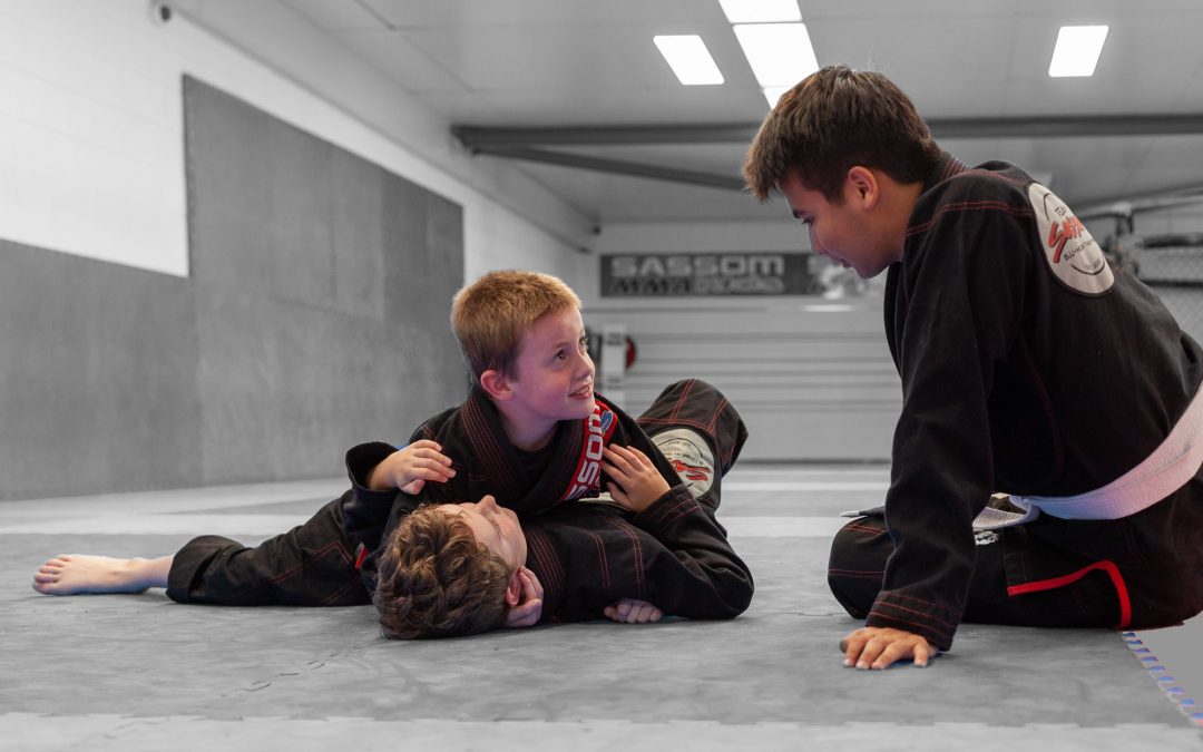 kids wrestling on the floor while being coached by a martial arts teacher in Brisbane