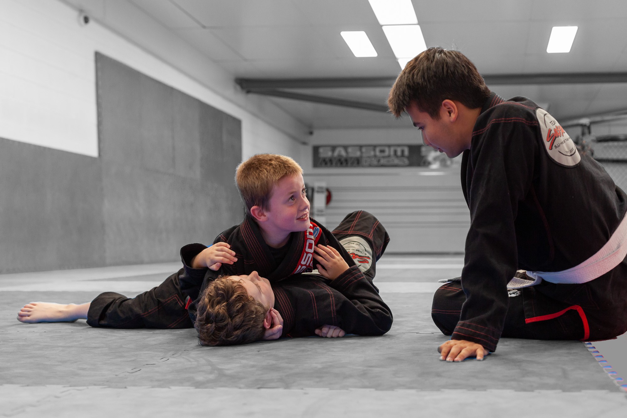 kids wrestling on the floor while being coached by a martial arts teacher in Brisbane<br />
